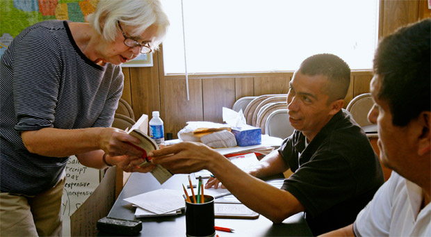 man handing book to woman