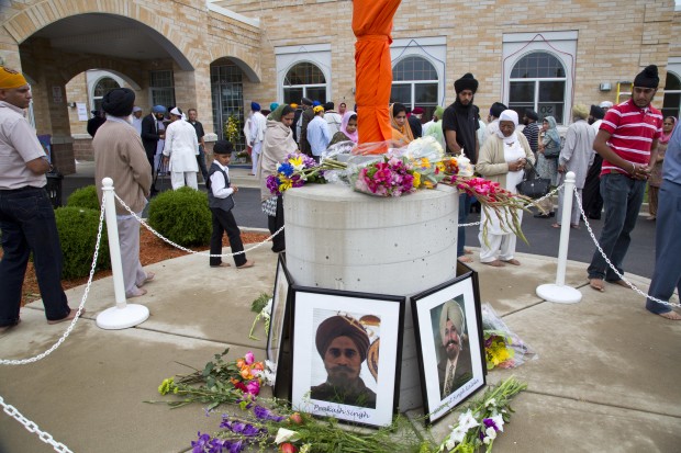 People walk around a flag pole outside the Sikh Temple of Wisconsin in Oak Creek, Wisconsin, the site of a hate-fueled, violent attack that left six members of the Sikh community dead.