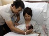 Nongyu Li, at left, holds his yet to be named newborn daughter alongside his wife Jennifer Gu