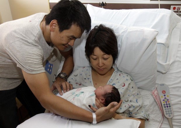 Nongyu Li, at left, holds his yet to be named newborn daughter alongside his wife Jennifer Gu