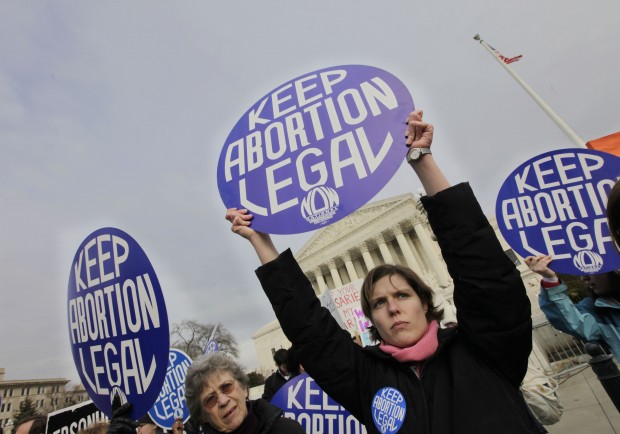 Abortion-rights activist and National Organization for Women (NOW) member Erin Matson, right, and others, holds up a signs