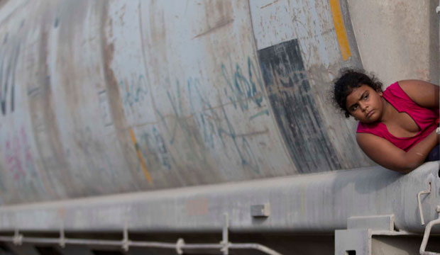 A young migrant girl waits for a freight train to depart on her way to the U.S. border, in Ixtepec, Mexico.