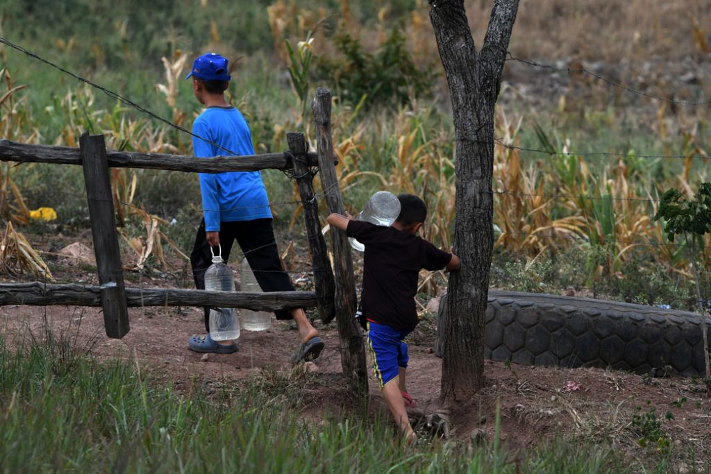 Children carry bottles of water near Los Laureles reservoir, close to the Honduran capital of Tegucigalpa, during a drought caused by climate change. 