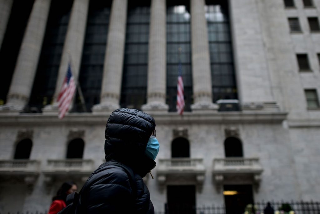 A woman wearing a face mask passes by the New York Stock Exchange in New York City, February 3, 2020.