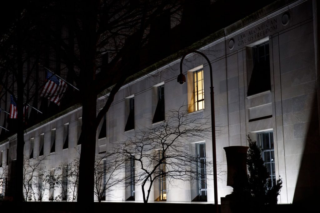 The U.S. Department of Justice building is seen on a March 2019 evening with one light on, Washington, D.C. 