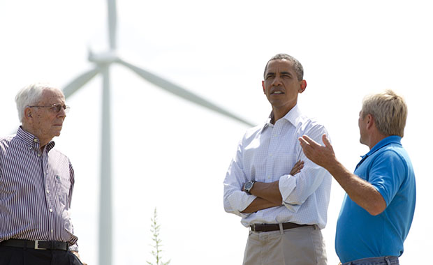 As wind turbines turn in the distance, President Barack Obama talks with Richard Heil, left, and Jeff Heil, on the Heil family farm, Tuesday, August 14, 2012, in Haverhill, Iowa, during a three-day campaign bus tour through Iowa.