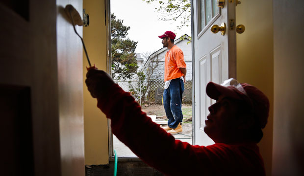 Victoriano Del La Cruz, a carpenter from Mexico, stands just outside of a basement entrance as Sergio Ajche from Guatemala finishes a painting job in New York.