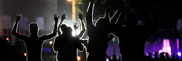 People raise their hands in the middle of the street as police wearing riot gear move toward their position in an attempt to get them to disperse, Monday, August 11, 2014, in Ferguson, Missouri.