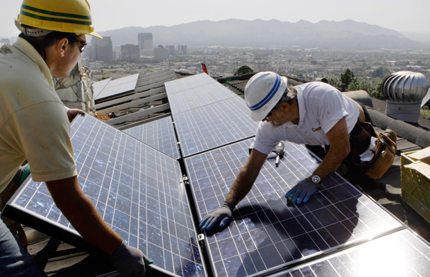 Edward Boghosian and Patrick Aziz, both employees of California Green Design, install solar electrical panels on the roof of a home in Glendale, California.