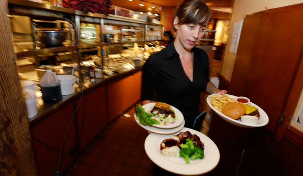 Wendy Harrison, a waitress at the Icon Grill in Seattle, carries food to a table as she works during lunchtime. 