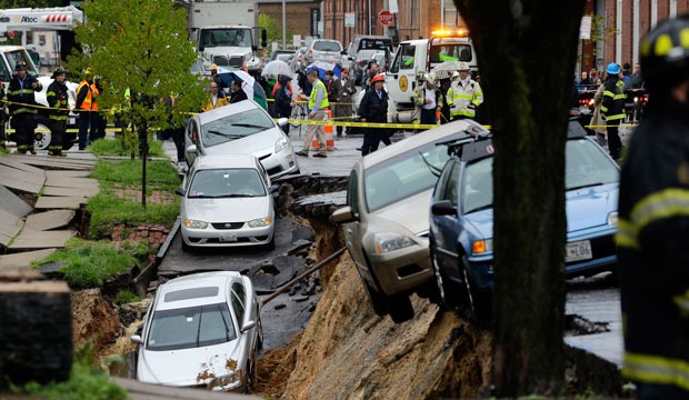 Cars sit on the edge of a sinkhole.