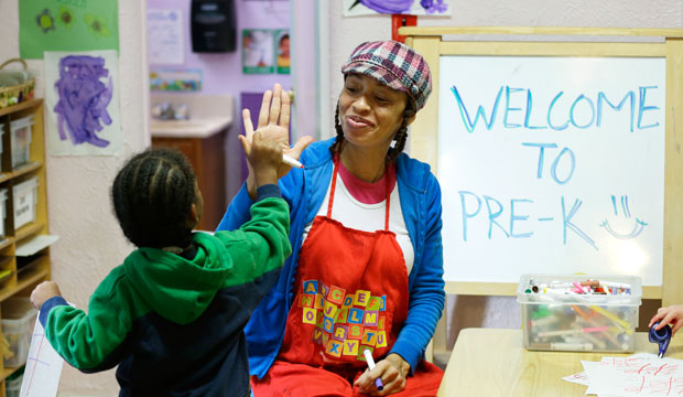 A teacher in a pre-K class gives a high-five, October 2014.