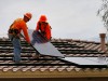 Electricians install solar panels to roof.