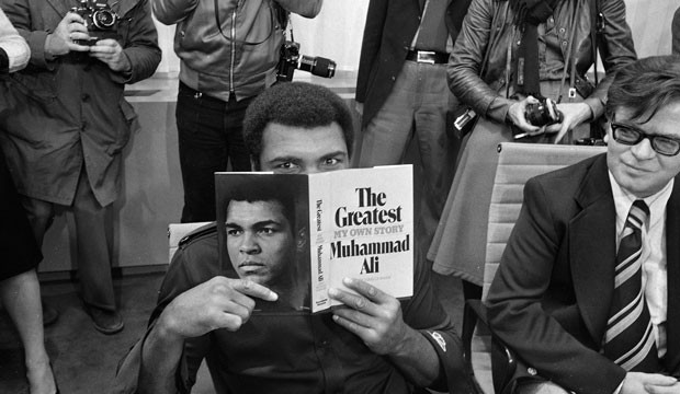 Muhammad Ali holds his autobiography.