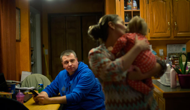 A man sits at the kitchen table as his wife holds their daughter in Harlan, Kentucky, on October 18, 2014.
