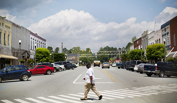 A pedestrian crosses a street in the main business section of Montezuma, Georgia, April 2014.